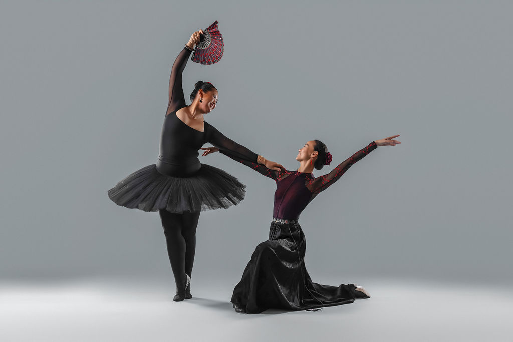 Two dancers in black costumes, one with a fan