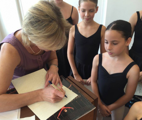 Bolshoi Master Teacher signing an autograph book for young ballet students